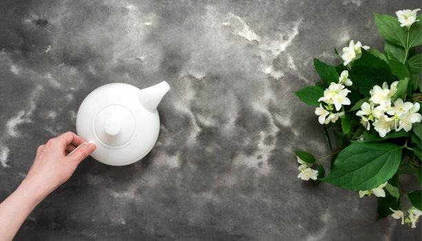 女子手捧白茶壶，茉莉花，黑白玉平躺。下午茶时间俯视图模板长网页横幅图片下载