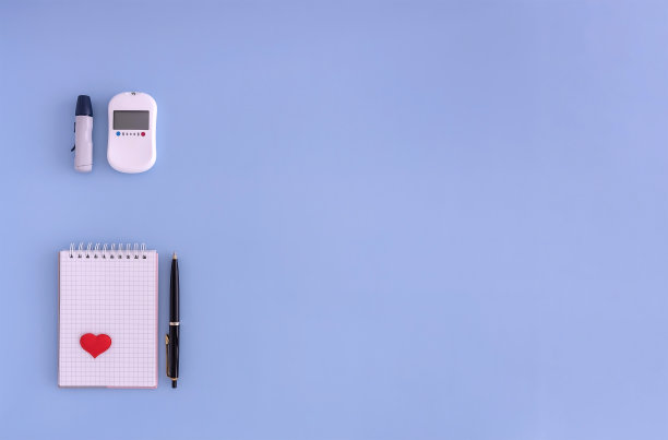 血糖仪，记事本，蓝色背景的笔。监测血糖水平的概念图片下载