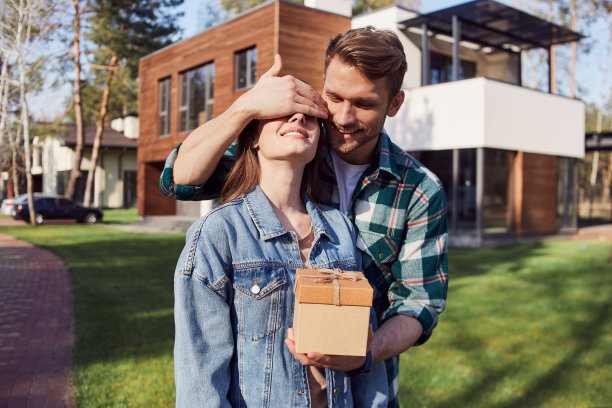 快乐的年轻男性拿着礼物，站在一个女人旁边图片下载