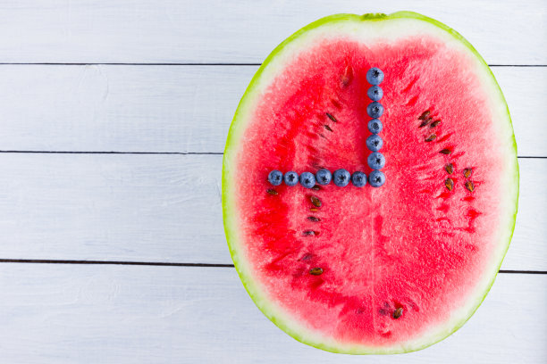 西瓜和蓝莓在白色的背景。半块西瓜放在木板上。素食的浆果。浆果的时钟指针。看从食物图片下载