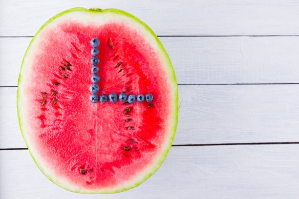 西瓜和蓝莓在白色的背景。半块西瓜放在木板上。素食的浆果。浆果的时钟指针。看从食物图片下载