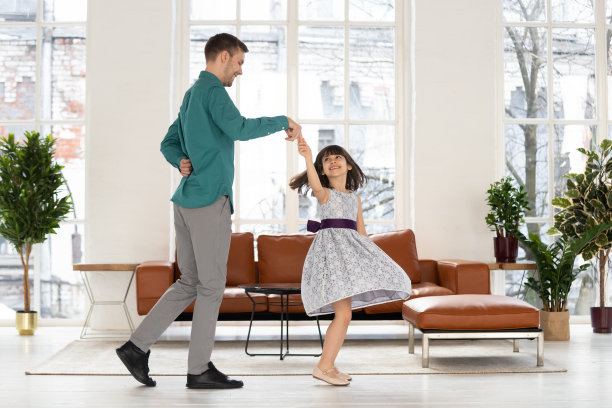 快乐慈爱的父亲牵着可爱的女儿跳舞。图片下载