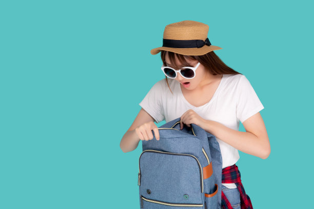 美丽的肖像年轻的亚洲女子戴太阳镜和帽子微笑打开背包旅行夏季旅行假期在度假孤立的蓝色背景，游客快乐的亚洲女孩是自信的包。图片下载