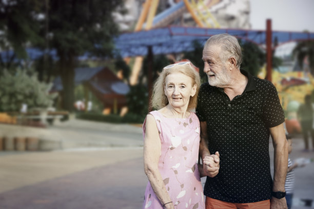 老年夫妇花时间一起在夏季周末的主题公园，老年人在游乐场闲逛和有乐趣。爷爷和奶奶拍的照片享受他们的时间在游乐场图片下载