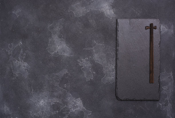 灰色混凝土背景下的黑色石头上的筷子图片下载