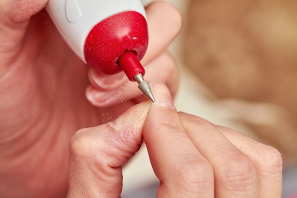 女人在家里用电动指甲锉锉指甲。电动指甲锉指甲修脚钻。在家修指甲。特写，选择性聚焦图片下载