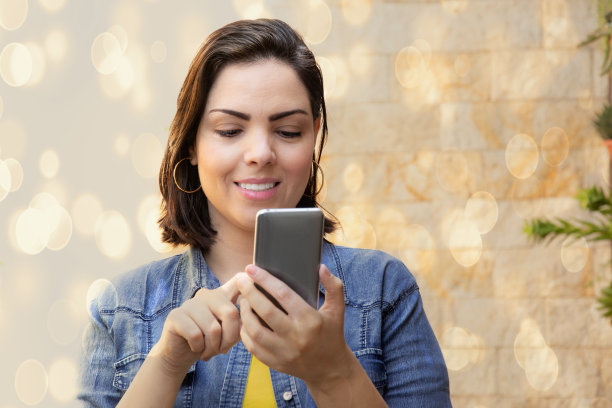 女人看手机在阳光明媚的一天与散景的背景图片下载