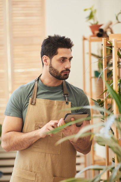 男子检查室内盆栽植物图片下载