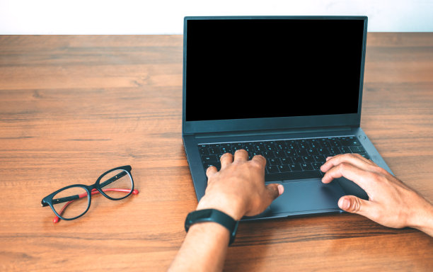 手放在木制背景上的笔记本电脑键盘上图片下载