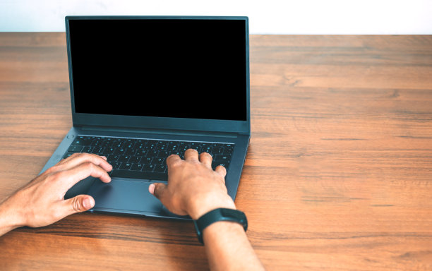 手放在木制背景上的笔记本电脑键盘上图片下载