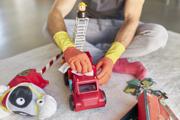 一名男子戴着橡胶手套，用消毒湿巾消毒和清洁儿童玩具的照片图片下载