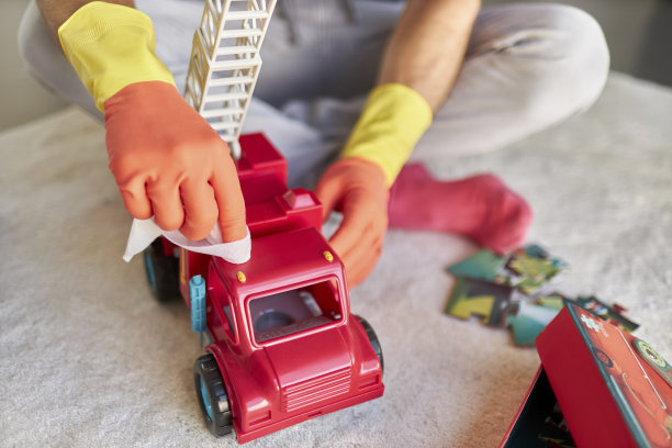 一名男子戴着橡胶手套，用消毒湿巾消毒和清洁儿童玩具的照片图片下载
