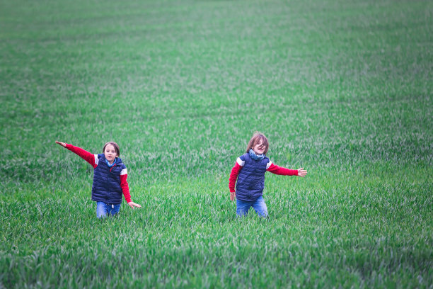 十几岁的孩子，男孩，在一个阴天在绿色的田野上奔跑图片下载
