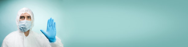 身着防护服，带着医用面具，蓝色背景的男人图片下载