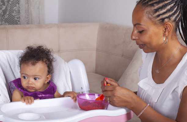 非裔美国母亲用勺子喂她的婴儿图片下载