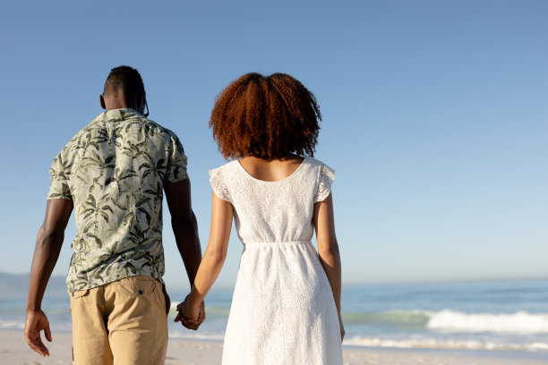 在海滩上牵着手的混血夫妇图片下载