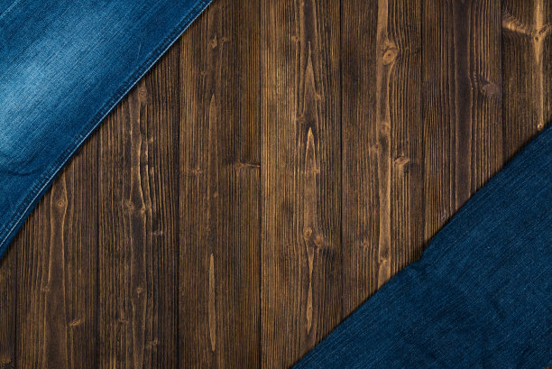 磨损牛仔裤或蓝色牛仔裤牛仔收集在粗糙的深色木制桌子背景，顶部视图与拷贝空间，旧的时尚概念。图片下载