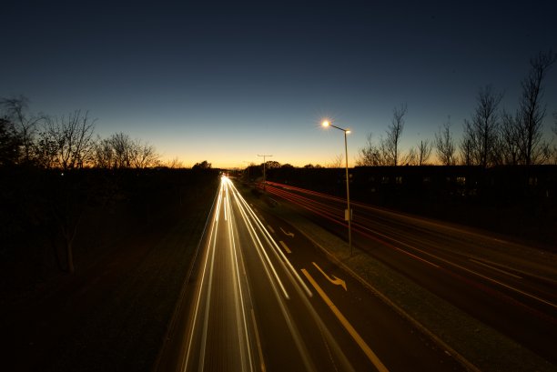 夕阳下的道路上模糊了汽车的前灯和尾灯。图片下载