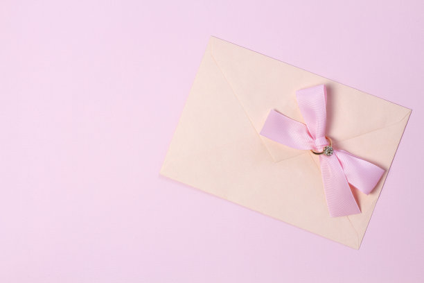 一个粉色蝴蝶结的信封，淡粉色背景上的金戒指。平的风格。图片下载