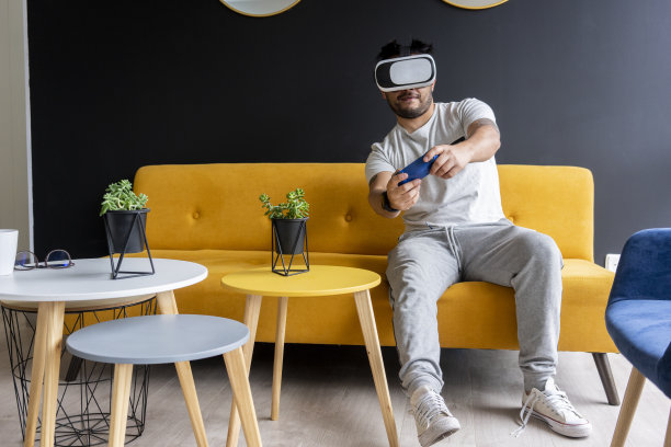 被COVID-19隔离的男子戴着虚拟现实眼镜玩电子游戏图片下载