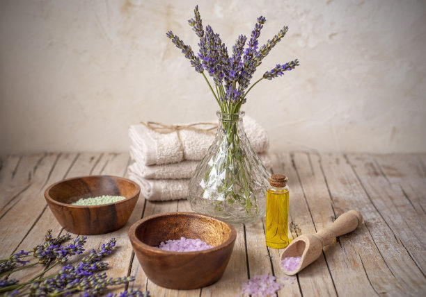 装有精油的瓶子和装有海盐的碗放在木桌上。薰衣草化妆品，水疗和芳香疗法的概念图片下载
