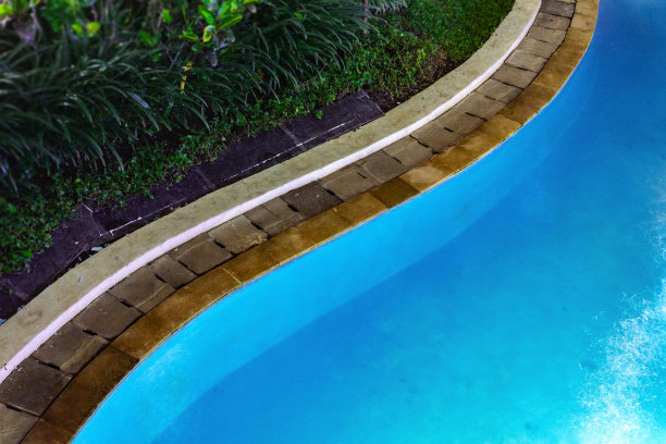 游泳池在晚上与郁郁葱葱的绿化和照明的家庭设计和景观图片下载