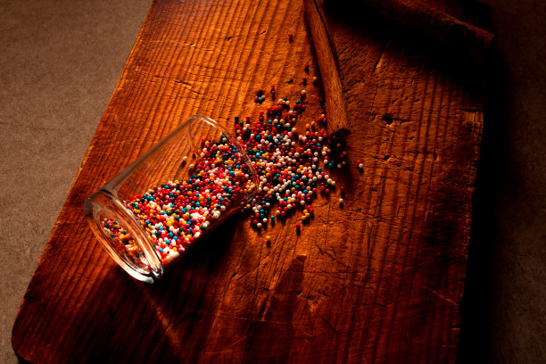 彩色的糖果和糖果从玻璃洒在旧的厨房木板上，肉桂棒。有选择性的重点。圣诞节，烹饪，厨房，食物和家庭烘焙概念照片。图片下载