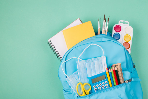 医疗保健的概念。研究检疫期间的概念。上面的头顶上的背包照片充满了彩色的文具和两个蓝色面具孤立在绿松石背景图片下载