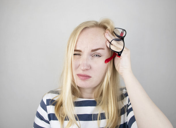 一个女人用他疲惫的双手在白色的背景上揉揉他的眼睛。来自电脑和工作的眼睛疲劳的概念。眼睛和前额疼痛，偏头痛，眼疾图片下载