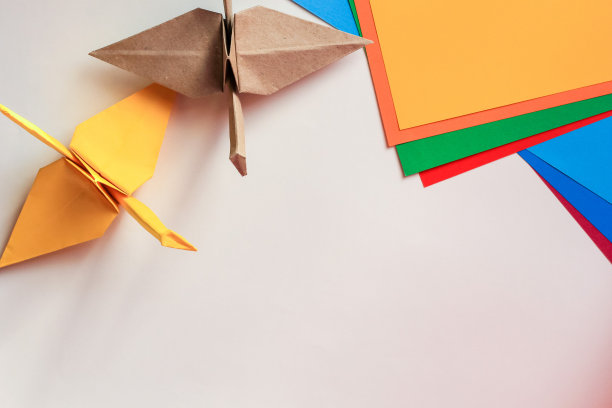 手工折纸鹤和黄色纸躺在白色的背景和各种彩色的学校和办公用品。孩子的创意、艺术观念，回到学校。拷贝空间，俯视图。图片下载