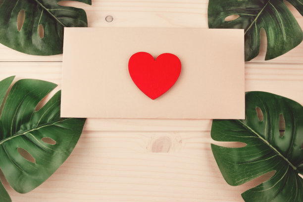 平铺红木心躺在工艺信封在质朴的桌子与三张怪物在角落图片下载