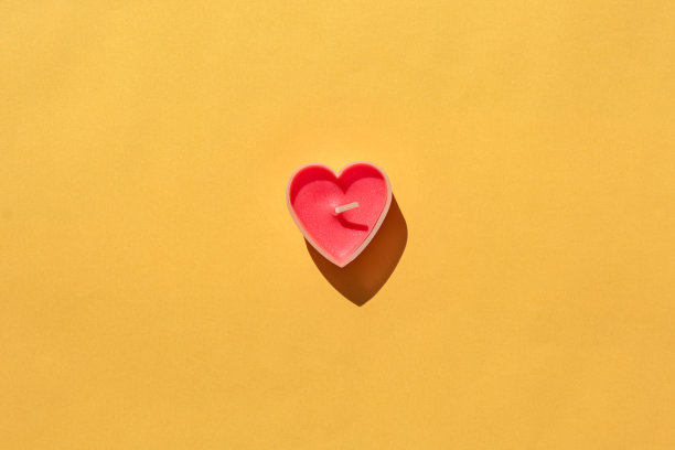 黄色背景上的心形蜡烛。隔离。放置标签的位置图片下载