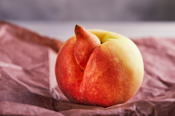 畸形水果或蔬菜：紫色纸上的一个非常难看的变异桃子，畸形水果需求不高图片下载