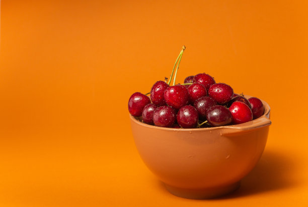 樱桃与水滴碗在赤陶土背景。水果碗。美味的食物。副本的空间。高质量的特写照片。图片下载