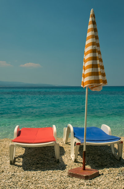 海边有一副日光浴躺椅和一把雨伞图片下载