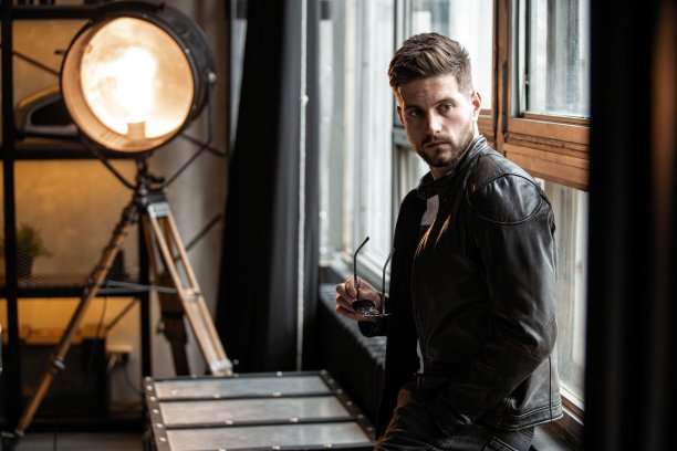 年轻和自信。英俊的年轻人坐在窗前。图片下载