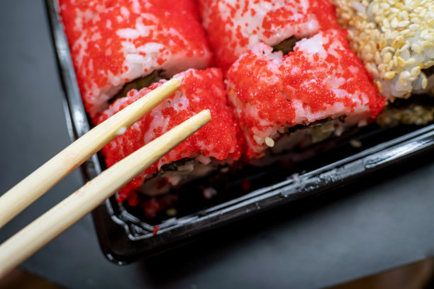 木棒躺在红色的寿司上，黑色的背景特写。日本料理的概念。从上方俯瞰照片图片下载