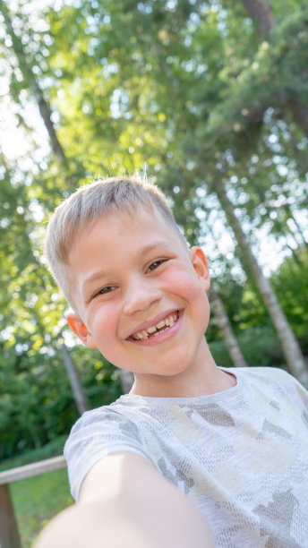 真实有趣的小男孩在自拍和大笑。微笑可爱的男孩拍照和视频聊天与家人。垂直的照片。图片下载