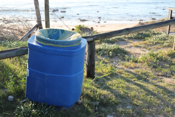 海边的蓝色塑料垃圾桶。这张图片可以用来代表海滩清洁的概念。图片下载