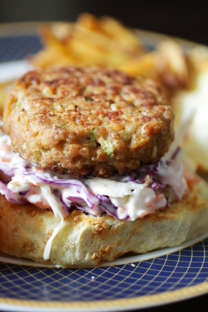 这是一盘自制鸡肉汉堡的特写图片，上面放着鸡肉肉饼，上面放着凉拌沙拉和蛋黄酱图片下载