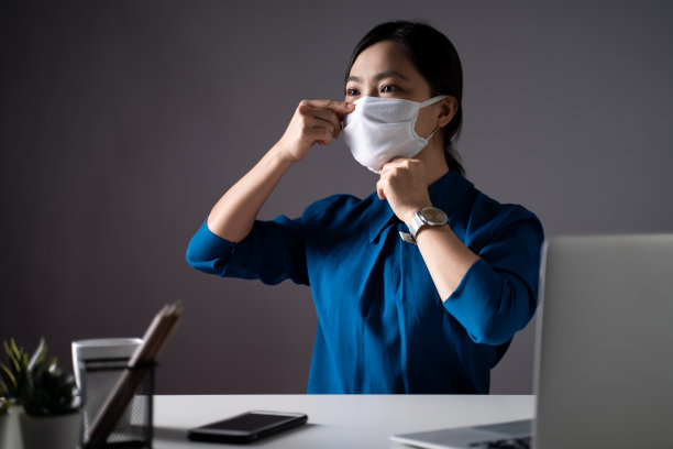 亚洲女性戴着防护面罩在办公室用笔记本电脑工作。亲密。居家办公预防COVID-19概念。图片下载