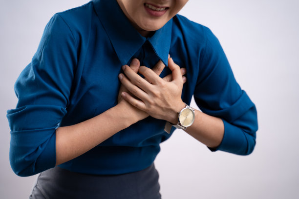 一名亚洲妇女因胸痛而不适，独自站在背景上。图片下载