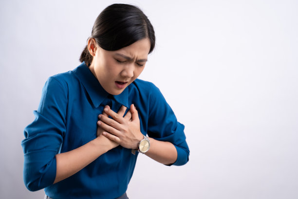 一名亚洲妇女因胸痛而不适，独自站在背景上。图片下载