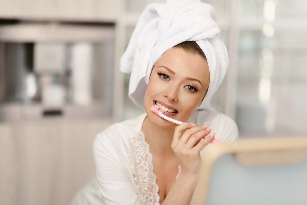 一个女人正在刷牙。早上的口腔卫生。特写与复制空间。有魅力的女孩，早上淋浴后头戴浴巾图片下载