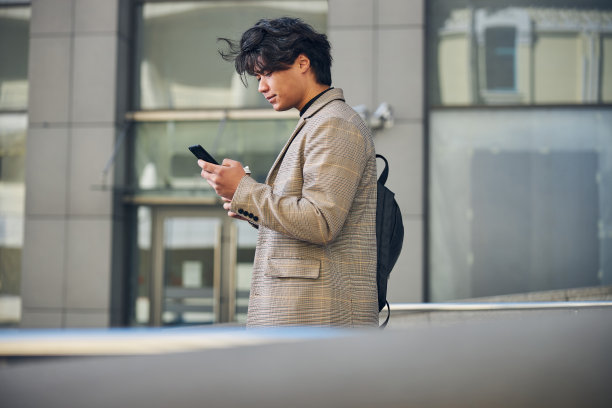 英俊的年轻人在户外使用手机图片下载