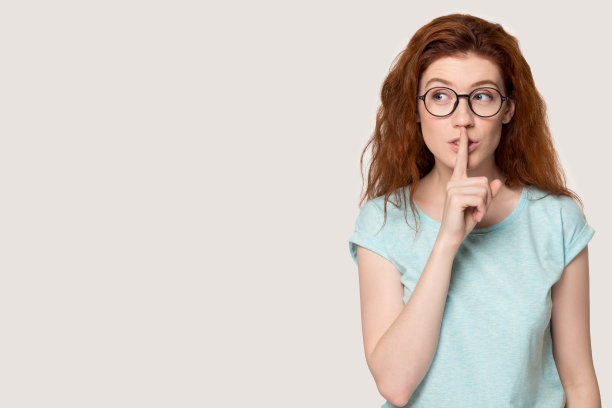 年轻的红头发女人做着安静的手势。图片下载