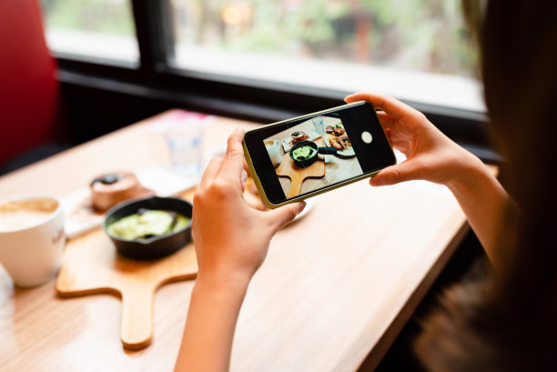 一名女子正在用智能手机给她的食物拍照。图片下载