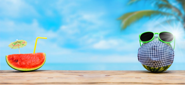 西瓜与太阳镜和面具在夏天的海滩背景。与他人保持至少2米或6英尺的社交距离。图片下载