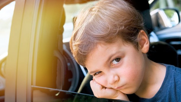 一个非常沮丧沮丧的小男孩望着车窗外，他不想再回到学校去了图片下载