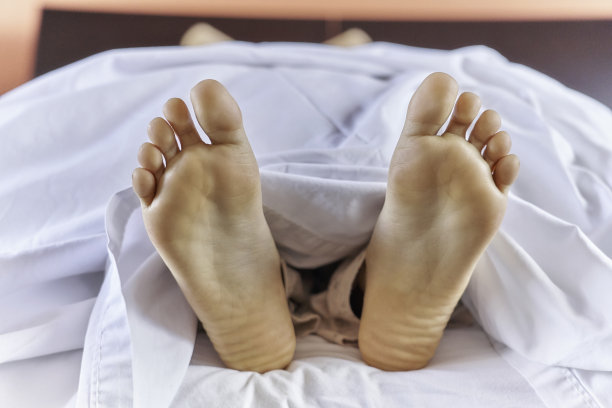 西班牙年轻女子近脚躺在床上图片下载